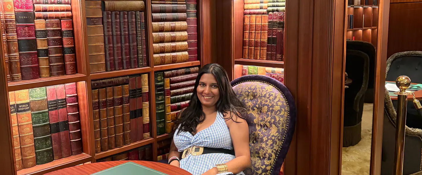 Shilika Jain seated in a wood-panelled library lounge lined with leather-bound books